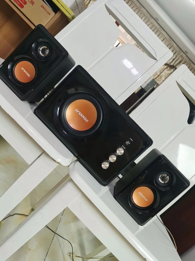 Black speaker system on wooden desk showing ports and controls